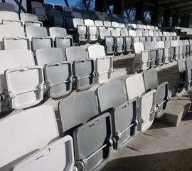 Many rows of white - grey plastic seats in the stadium