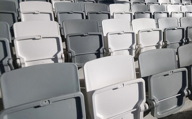 Many rows of white - grey plastic seats in the stadium