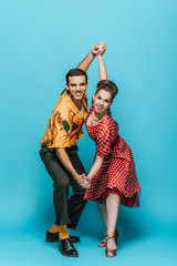 elegant dancers holding hands while dancing boogie-woogie on blue background