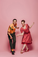 young dancers looking at camera while dancing boogie-woogie on pink background