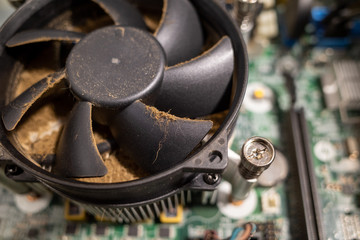 a very dirty computer fan inside a computer is cleaned by a vacuum cleaner