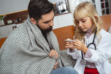 Daughter is taking father temperature with thermometer