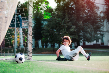 Children's soccer football - a match of young children on the football field. Young goalie. Kids - soccer champion. Boy goalkeeper in football sportswear on stadium with ball. Sport concept.