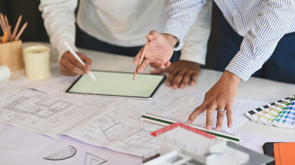Cropped shot of Architecture team are meeting/planning by using the blank white screen tablet on the desk.