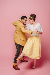 elegant dancers holding hands while dancing boogie-woogie on pink background