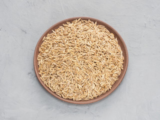 Spice cumin (jeera) in clay plate on gray concrete background. Indian cuisine, ayurveda, naturopathy concept