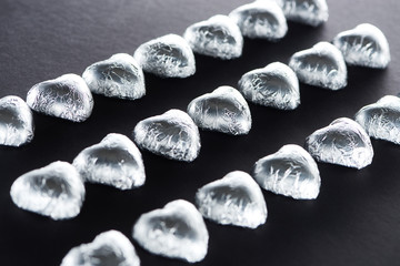 Heart shaped candies in foil on black background