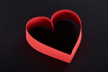 Obraz premium Red paper in heart shape isolated on black