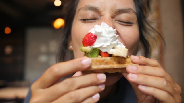 Young Cute Girl Eating Delicious Vegan Waffles With Whipped Cream And Fruits On Top. Close Up Portrait. 4K Slowmotion.