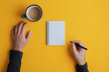 Top view of a man ready to write in his blank note pad