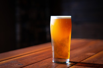 glass of beer in sunlight on wooden table