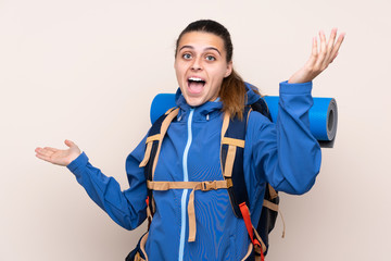 Young mountaineer girl with a big backpack over isolated background with surprise facial expression