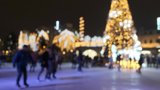Ice skate during Christmas holidays blurred. People skating on an outdoor skating rink in winter at night. Defocused scene 4k
