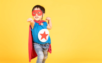 Cute little Asian child boy playing superhero on the yellow wall background. Superhero , Success...