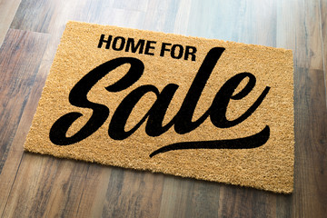 Home For Sale Welcome Mat On A Wood Floor Background