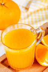orange juice in glass and oranges on wooden table