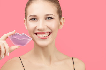 Happy smiling woman holding a mask near her lips. pink background