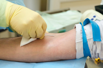 donation. blood transfusion. a hand in a medical glove injects a needle into a vein. soft focus. blood and bone marrow donation.