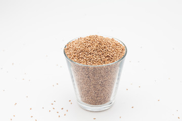 Sesame seeds in glass cup on a white