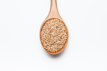 Toasted Sesame seeds in wooden spoon on white 