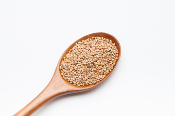 Toasted Sesame seeds in wooden spoon on white 