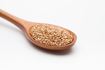 Toasted Sesame seeds in wooden spoon on white 