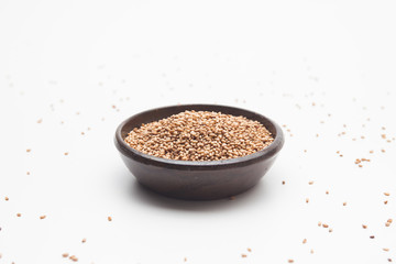 Toasted sesame seeds in crock bowl on white 