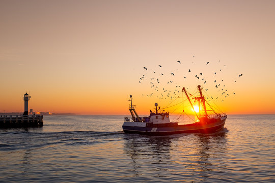 Fishing boat in front of the old wooden pier of Nieuwpoort (Belgium) at sunset