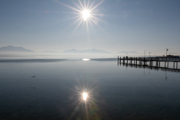 Panora,a Chiemsee  im Gegenlicht mit Bergblick und Sonne