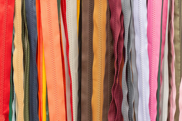 Background texture of zippers. a lot of zippers in different colors. vertical lines. sewing clothes, atelier, fabric and accessories shop.