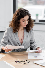 attractive account manager sitting at table and doing paperwork