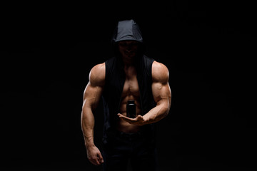 Obraz na płótnie Canvas Muscular bodybuilder with jar of protein on a dark background. Sports nutrition. Bodybuilding nutrition supplements, sport, workout, healthy lifestyle concept.