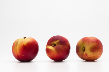 Row of Heavenly ripe peaches on white 