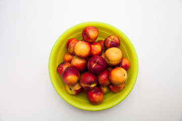 Ripe peaches in a green basket on a white