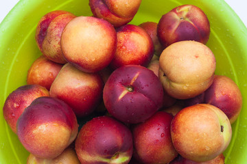 Ripe peaches in a green basket on a white