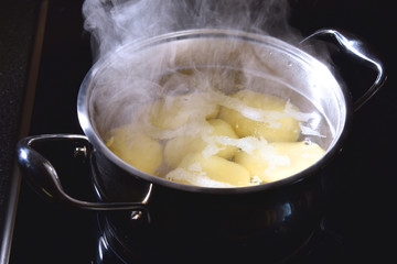 Potatoes boil in a saucepan on the stove
