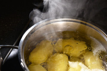 Potatoes boil in a saucepan on the stove