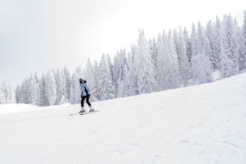 Fototapeta na wymiar Young woman skiing in mountain resort during winter vacation