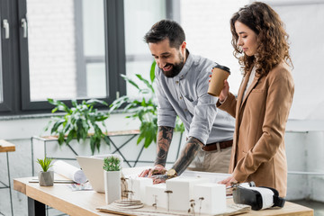Fototapeta premium smiling virtual reality architects looking at model of house