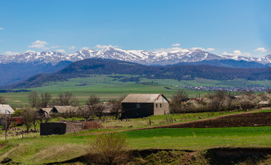 Rural landscape with village houses and snowy mountains