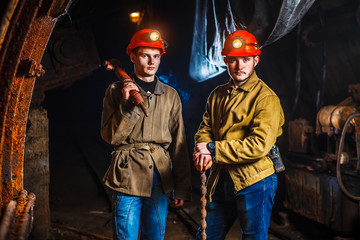 Miners in the process of working with tools in their hands. Coal mine. Two miners in the mine. Copy...