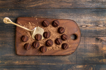 Homemade dark chocolate truffles in cocoa powder on wooden board, rustic dark background. Low light. Top view, copy space.