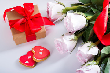 Homemade Valentines day heart cookies, pink roses and red gift box on white table
