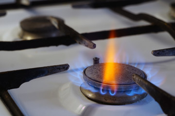 Flames from burning gas on a stove. Among the blue flame, one red stands out brightly. Cooking in the kitchen with a gas stove.