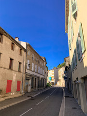 Fototapeta na wymiar Street with empty road and houses with orange shutters in France