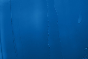 A liquid creamy texture of cosmetic products or acrylic paint smear of the blue classic blue color of the 2020 year. Cosmetic trendy background. Concept of the color of the year with copy space.