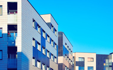 Apartment in residential building exterior. Housing structure at blue modern house of Europe. Rental home in city district on summer. Wall and glass high architecture for business property investment.