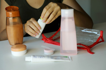 Fototapeta na wymiar Woman preparing travel kit cosmetics cream liquid for transporting on airplane