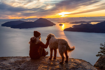 Adventurous Girl Hiking on top of a Mountain with a dog during a colorful sunset. Taken on Tunnel...