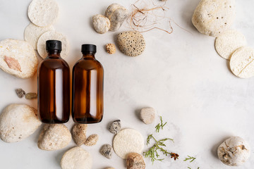 Naklejka na ściany i meble Glass bottles of shampoo and conditioner of body care cosmetics over Natural background of real tree bark, mosses, minerals sea, shell, luff, organic loofah decorative stones for cosmetic products